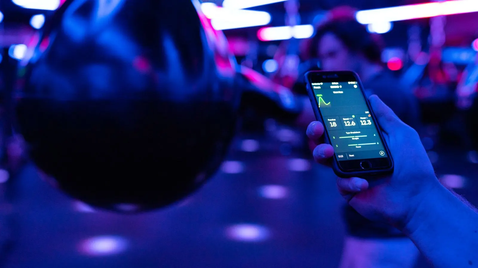 Person checking workout performance data on a smartphone in a gym