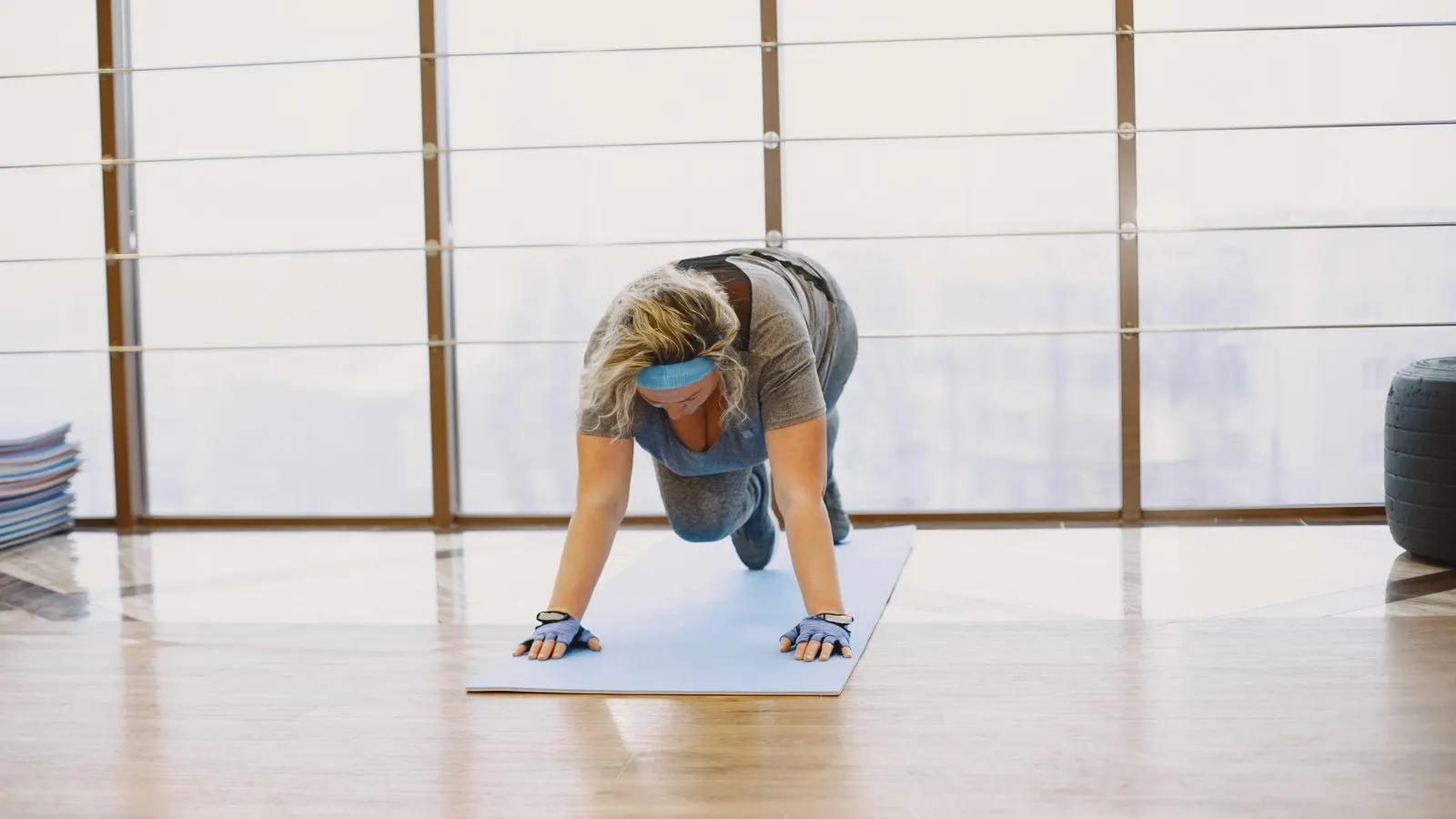 Woman performing a bodyweight plank exercise in a bright studio