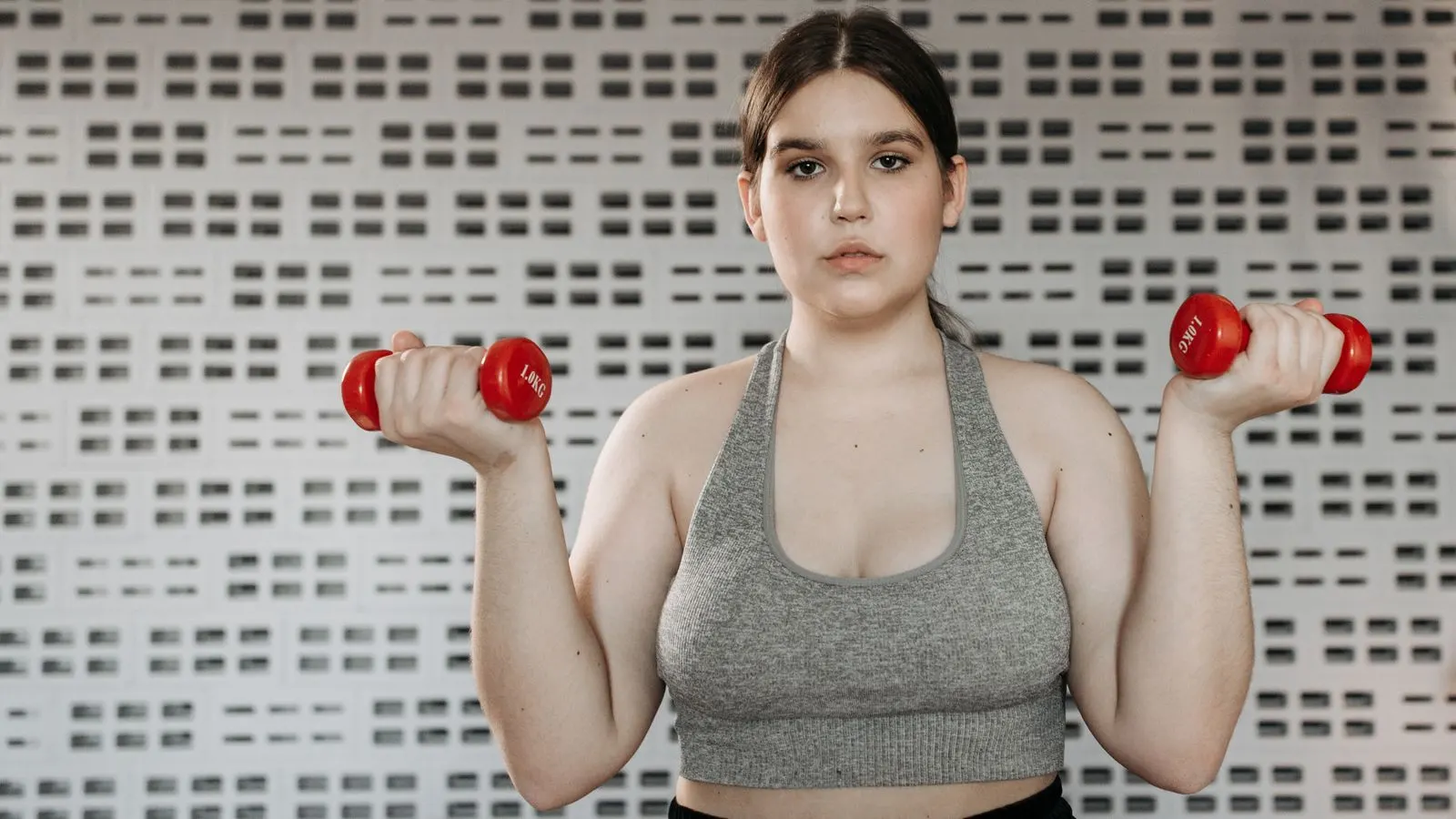 Woman performing an upper-body workout with red dumbbells